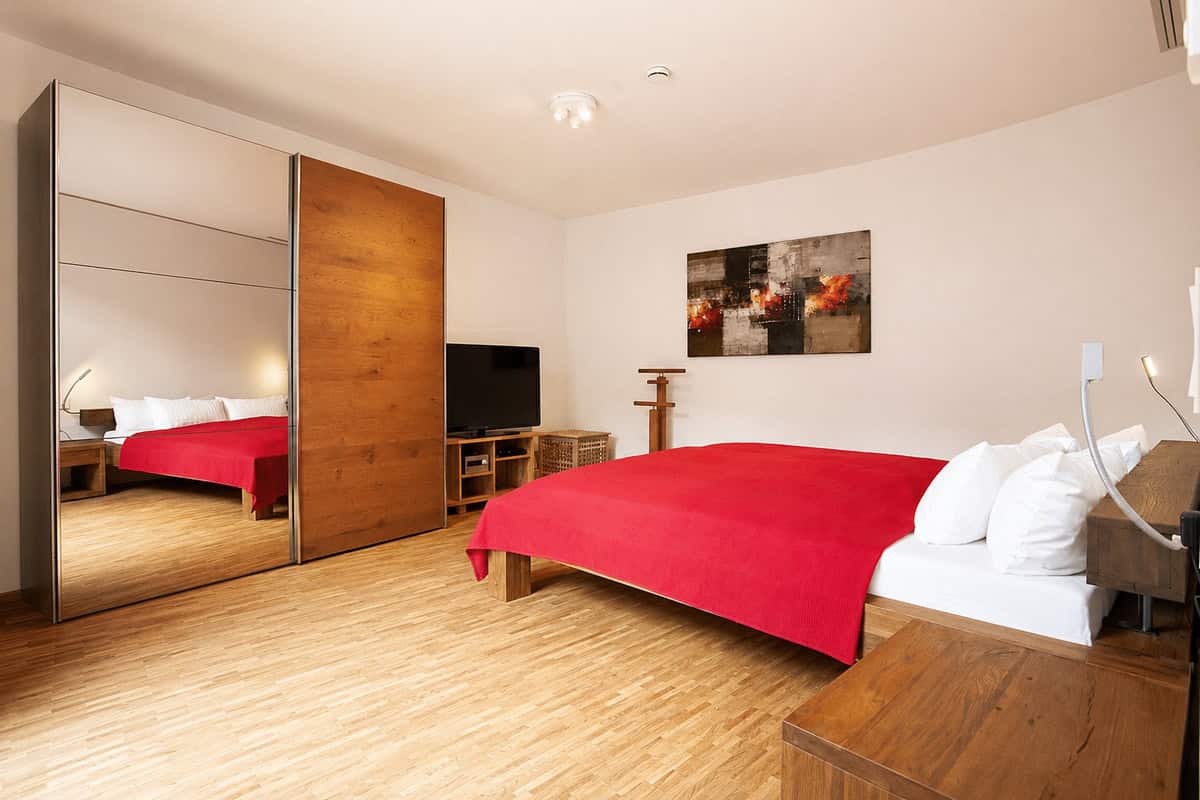 A furnished bedroom in Stuttgart with a red bedspread